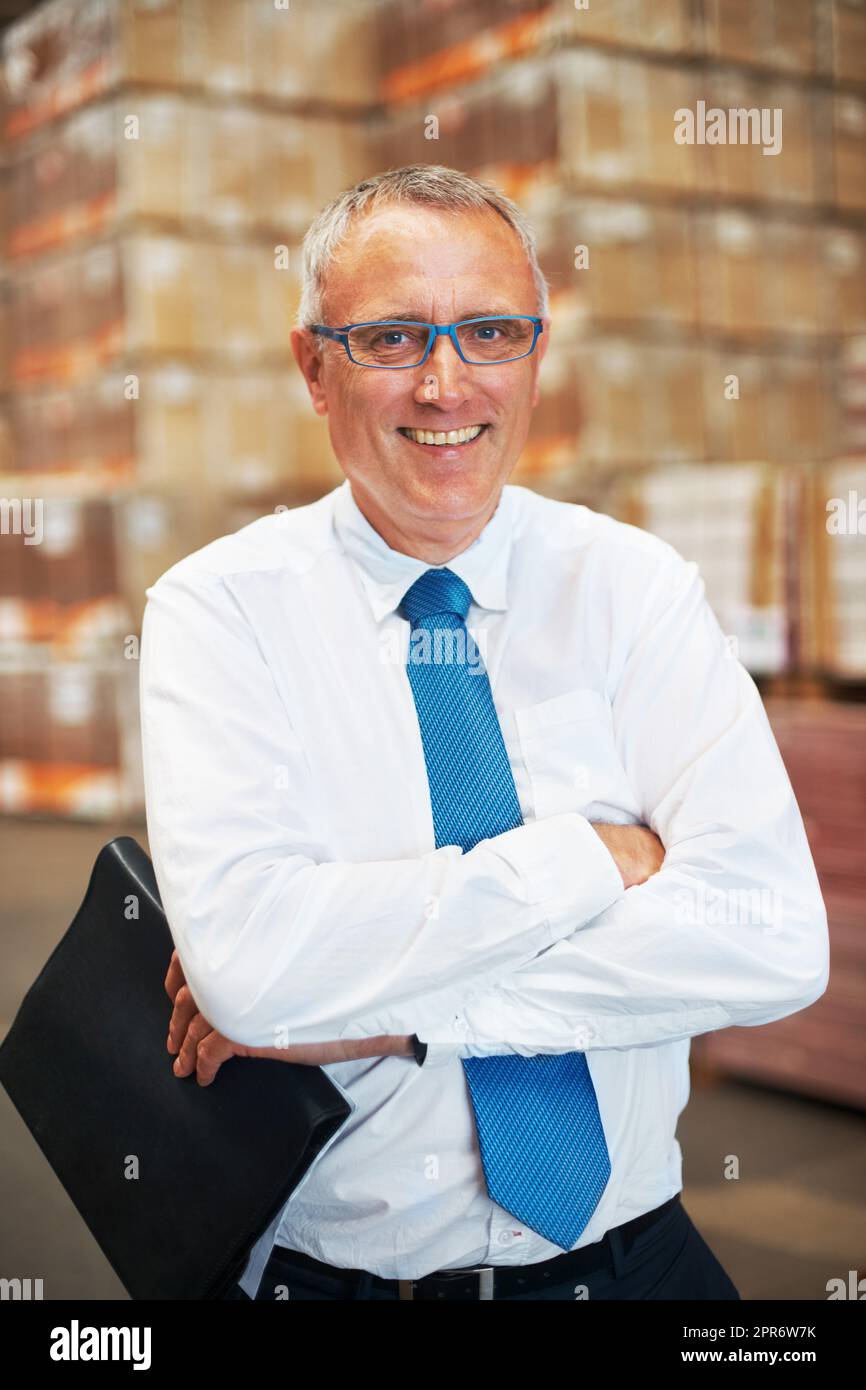 A storage warehouse manager standing in the factor amidst many boxes
