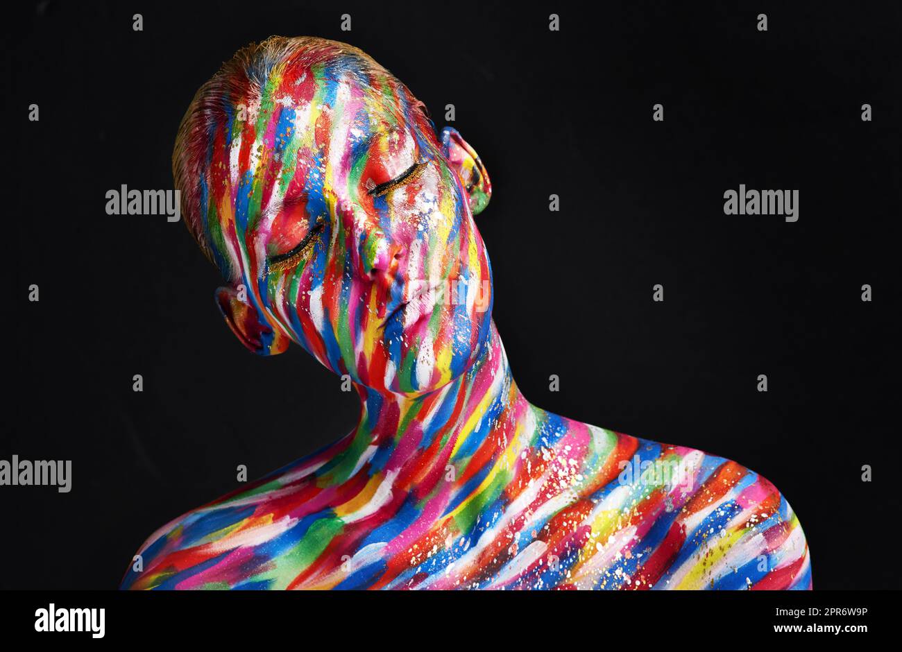 Dare to do beauty differently. Studio shot of a young woman posing with brightly colored paint on her face against a black background. Stock Photo