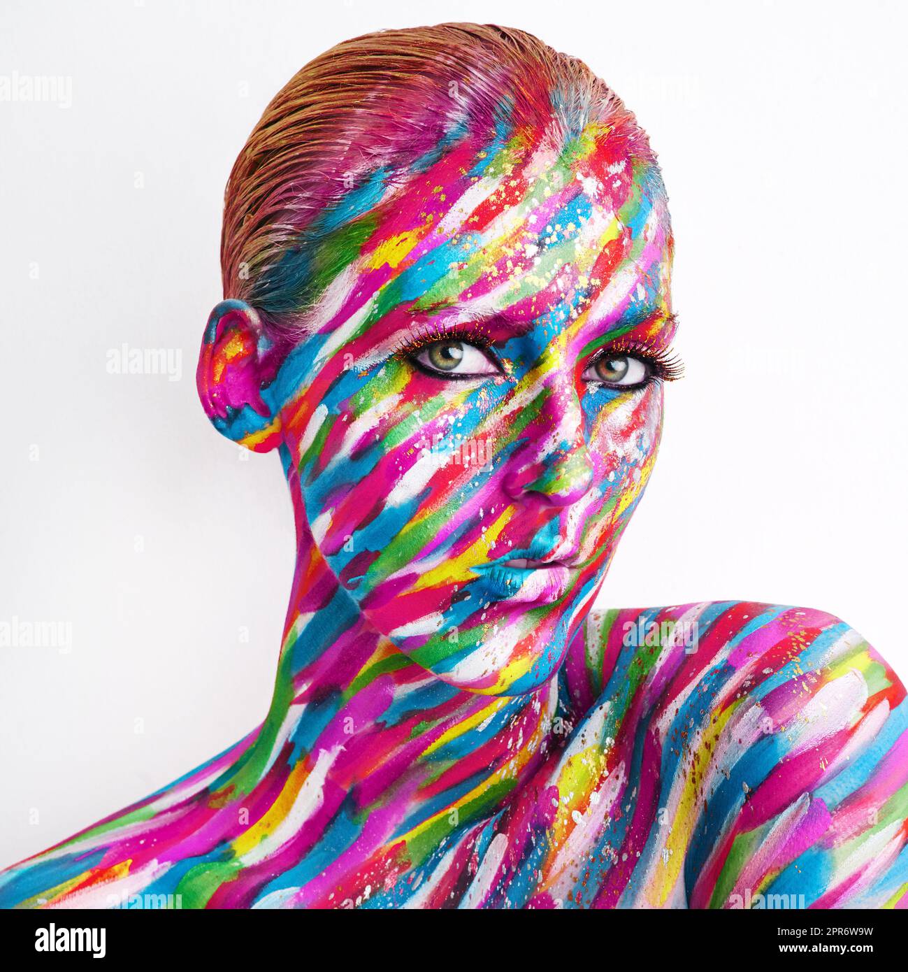 Theres art in beauty. Studio shot of a young woman posing with brightly colored paint on her face against a white background. Stock Photo