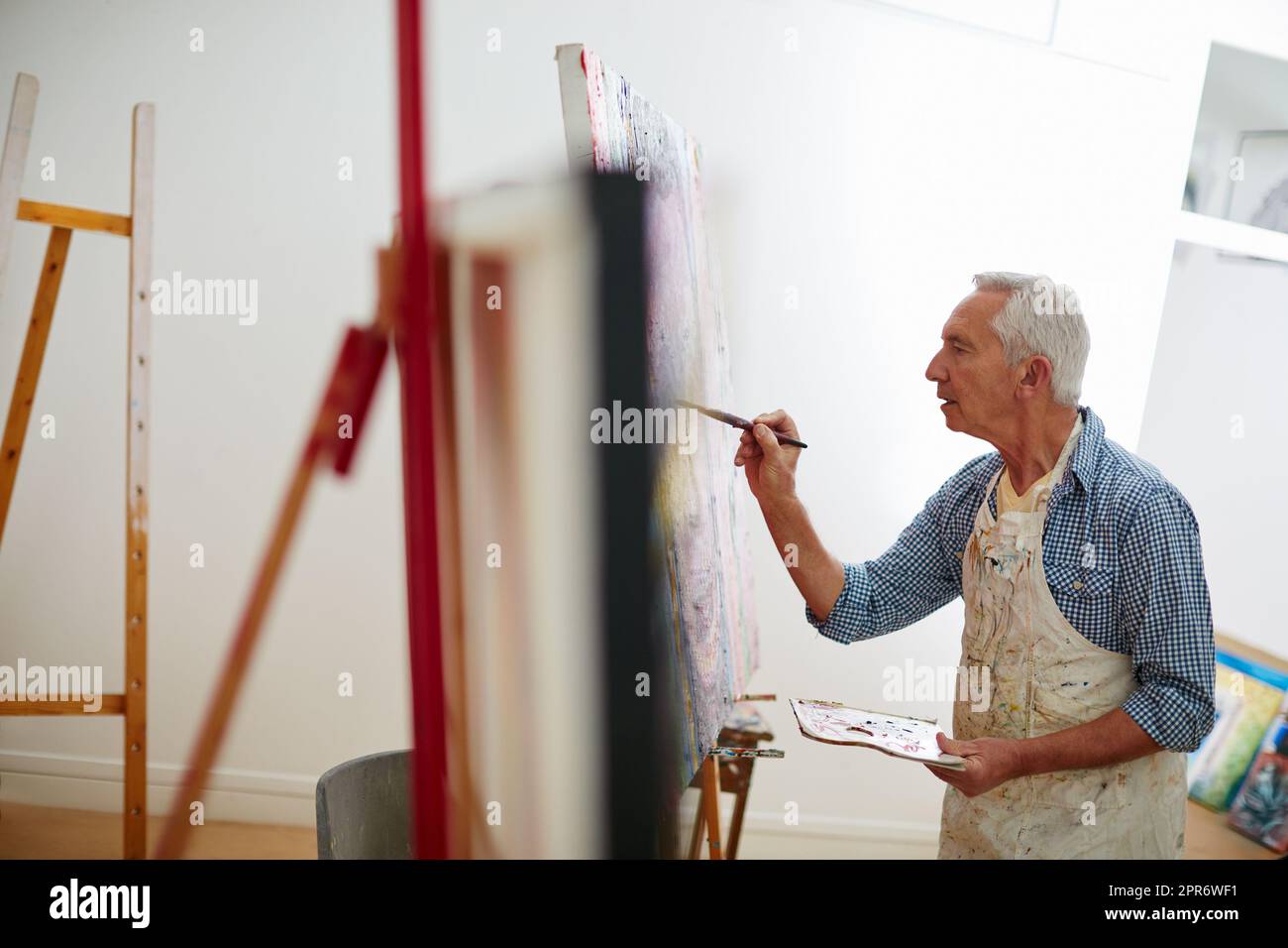 Art is the proper taste of life. Shot of a senior man working on a painting at home. Stock Photo