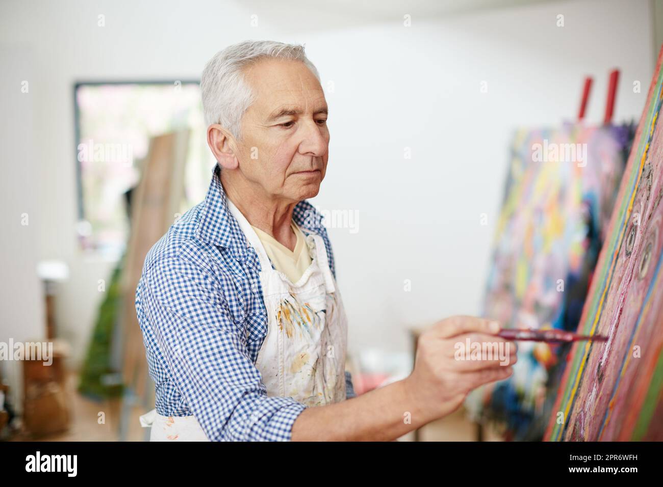 The creative adult is the child who survived. Shot of a senior man working on a painting at home. Stock Photo