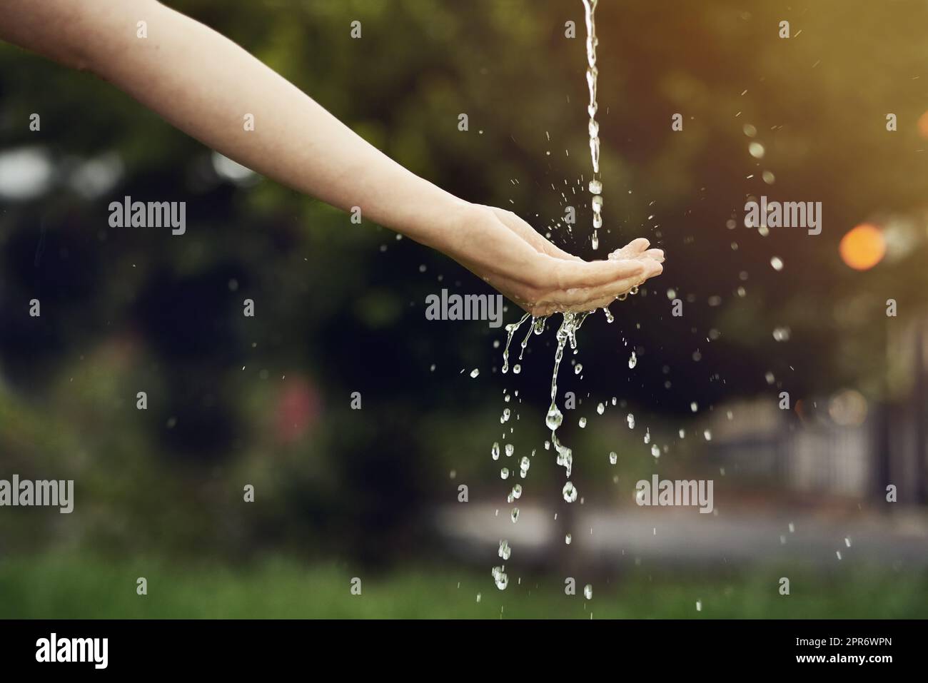 Make every drop count. Cropped shot of water running on a womans hand outside. Stock Photo