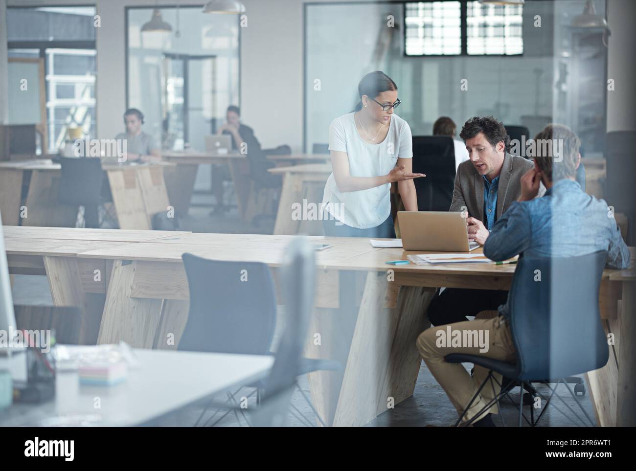 They make business happen. Through the glass shot of a group of colleagues working together in an office. Stock Photo