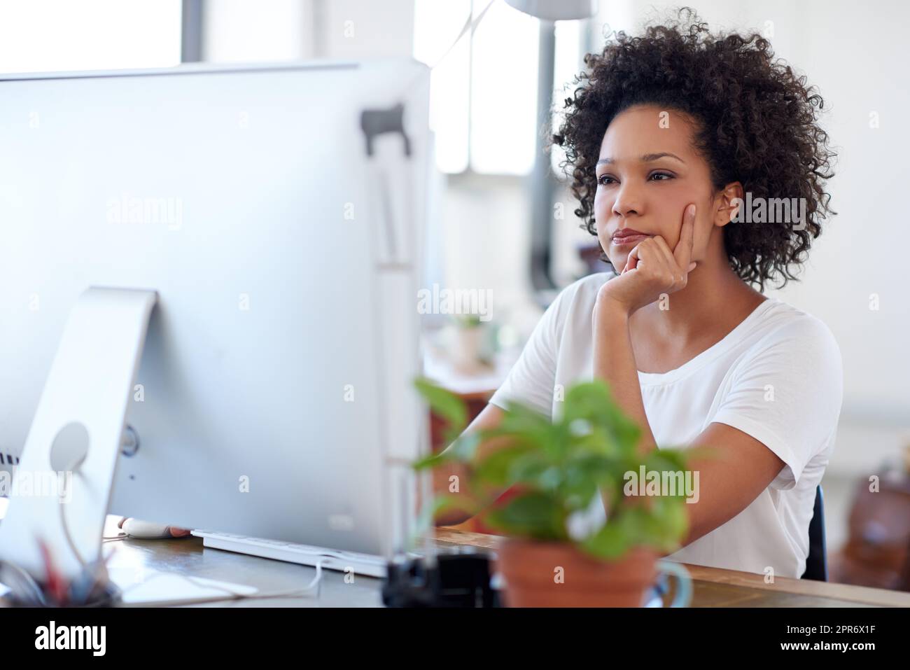 Keeping up to date with online developments. Beautiful creative professional looking intently at her pc in a bright open plan office space. Stock Photo