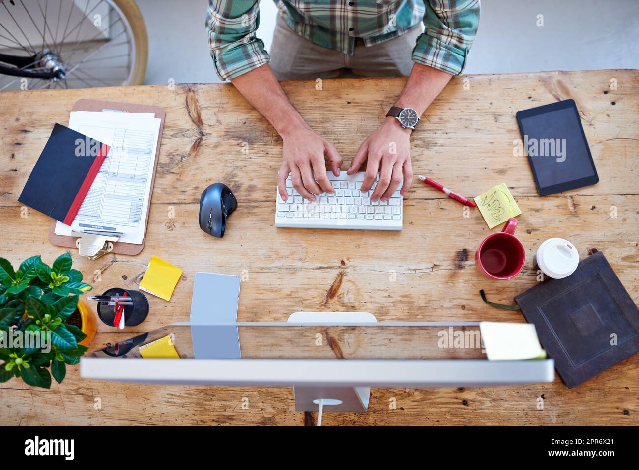 Creative professional at work. Overhead shot of a creative professionals desk while he is typing on his wireless keyboard. Stock Photo