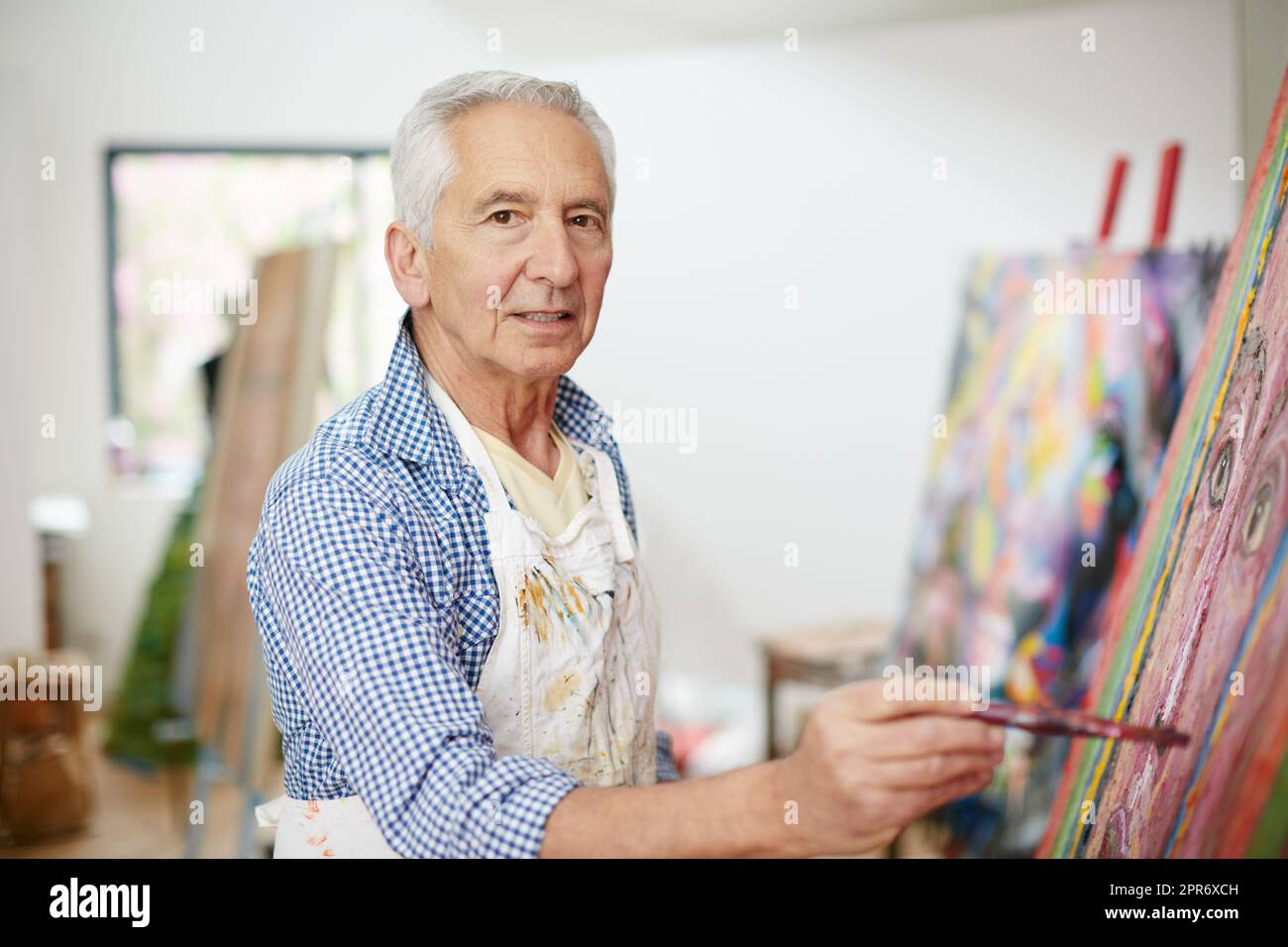 Life isnt about finding yourself, its about creating yourself. Shot of a senior man working on a painting at home. Stock Photo
