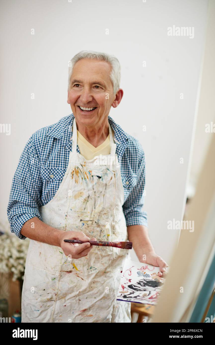 Take time to do what makes your soul happy. Shot of a senior man working on a painting at home. Stock Photo