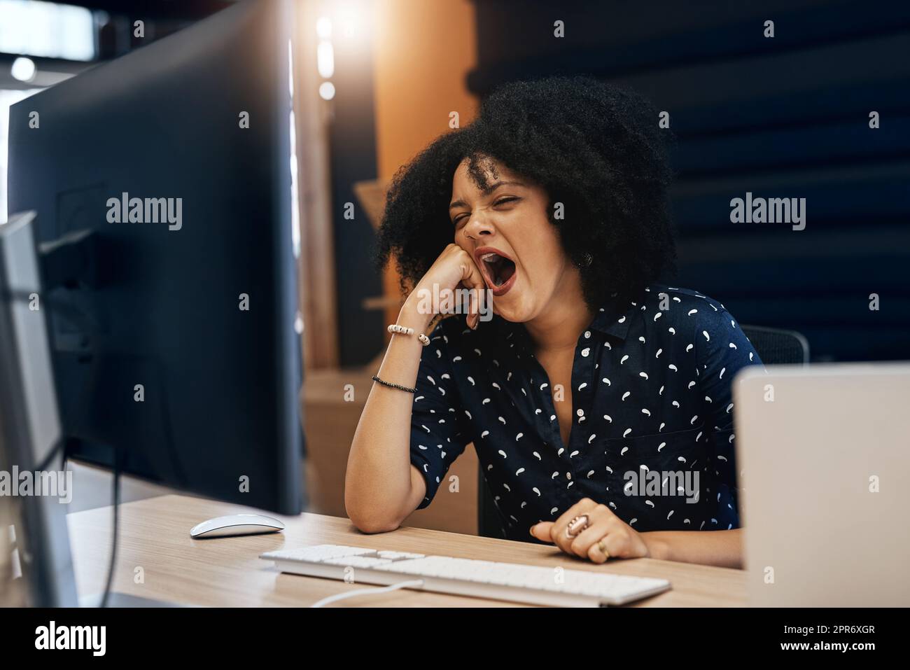 This work has made me so tired. Shot of a young tired looking female designer falling asleep behind her computer at the office during the day. Stock Photo