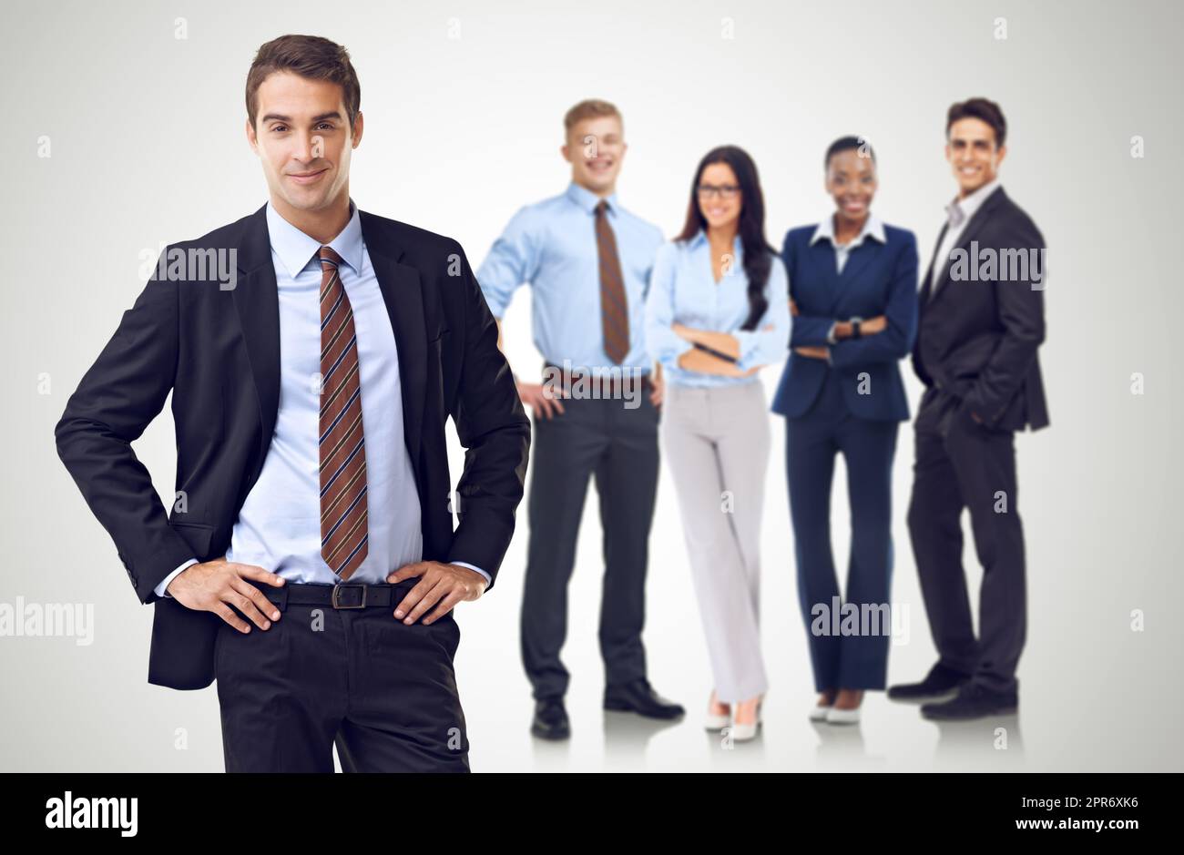 Unity through business diversity. Studio shot of a businessman with his hands on his hips standing in front of her colleagues. Stock Photo
