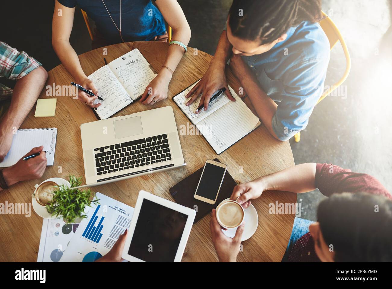 Online study resources can make your life so much easier. High angle shot of a group of students studying in a coffee shop. Stock Photo