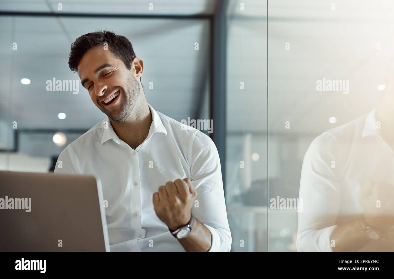Boom. Cropped shot of a handsome young businessman cheering while working on his laptop in the office. Stock Photo