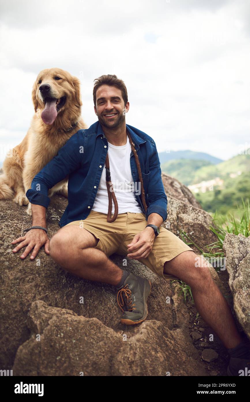 We just love hiking through the mountain. Cropped portrait of a handsome young man and his dog taking a break during a hike in the mountains. Stock Photo