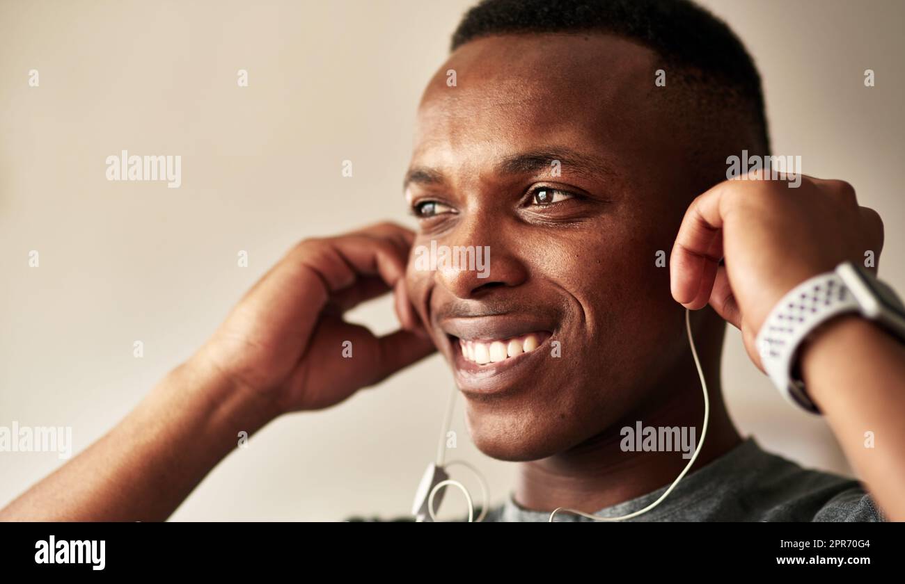 No one motivates me like music does. Cropped shot of a handsome young man putting his earphones in his ears. Stock Photo