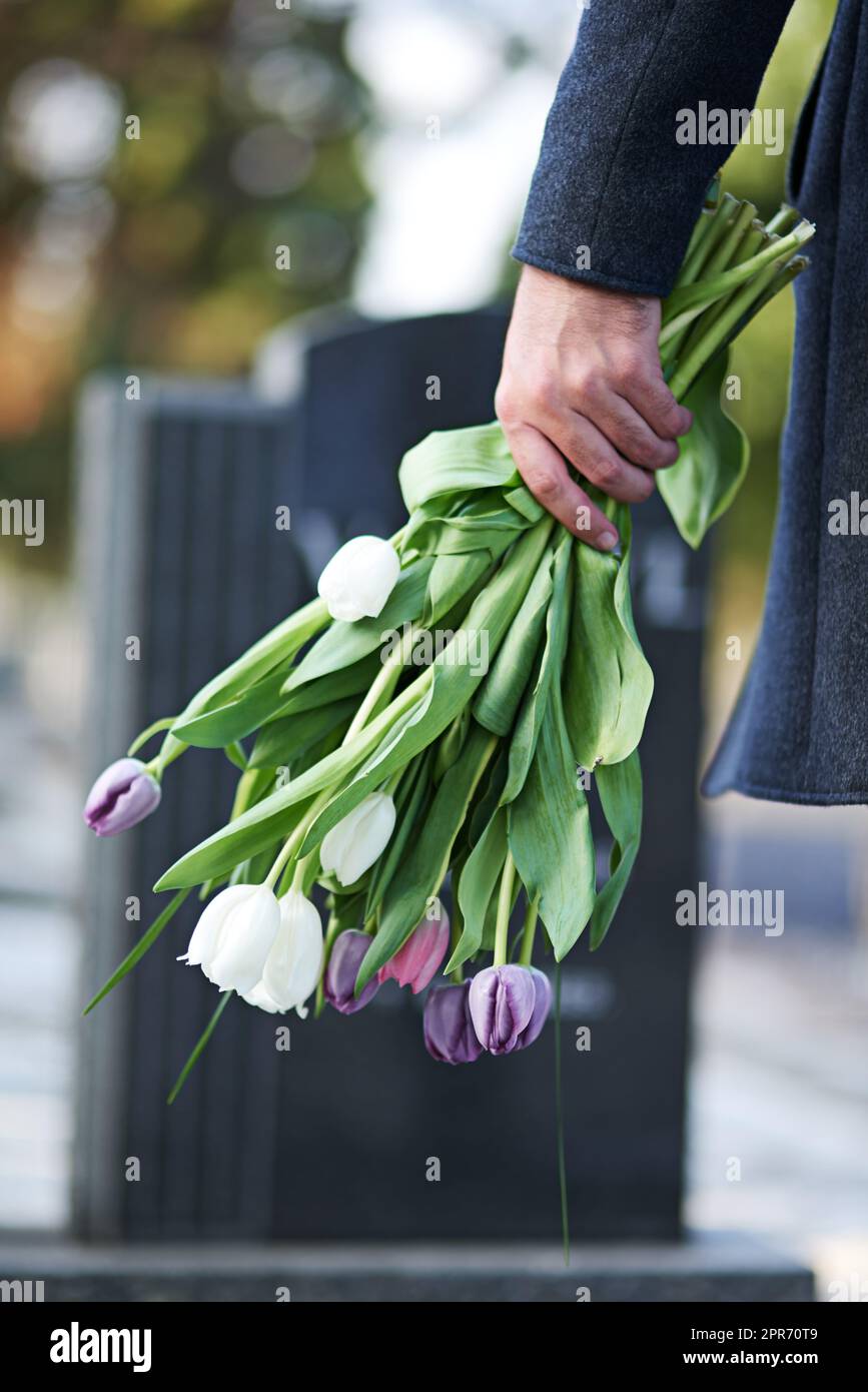 Gone but not forgotten. Cropped shot of a man visiting a gravesite with ...