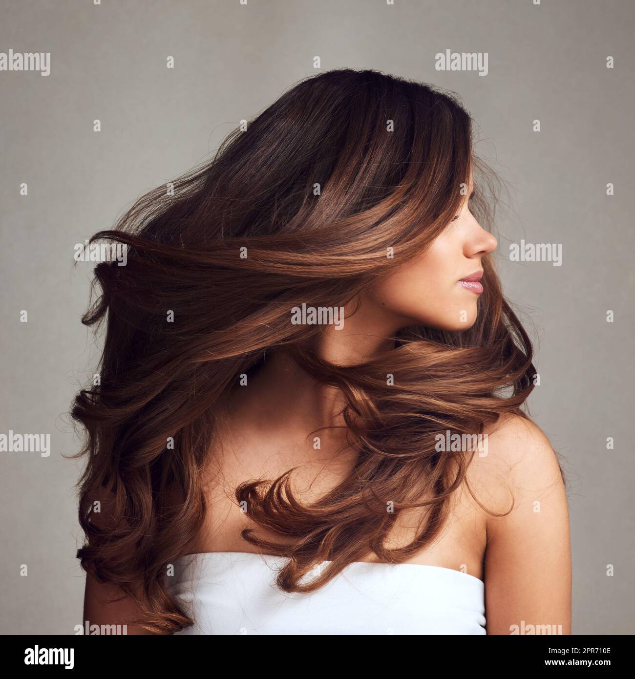 Making hairstory everyday with gorgeous hair. Studio shot of a young beautiful woman with long gorgeous hair posing against a grey background. Stock Photo