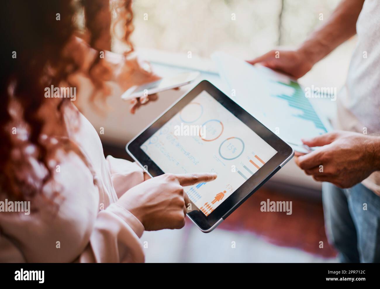 This is how are progression should look like. Shot of two unrecognizable peoples hands working on a tablet and looking at the businesss charts in the office. Stock Photo