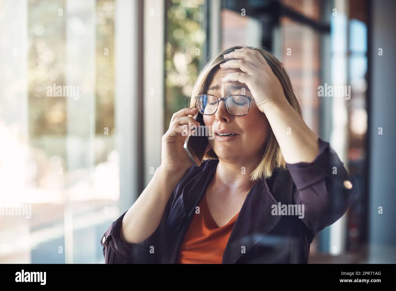 Say it isnt so. Shot of a young woman looking distraught while talking on a mobile phone in a modern office. Stock Photo