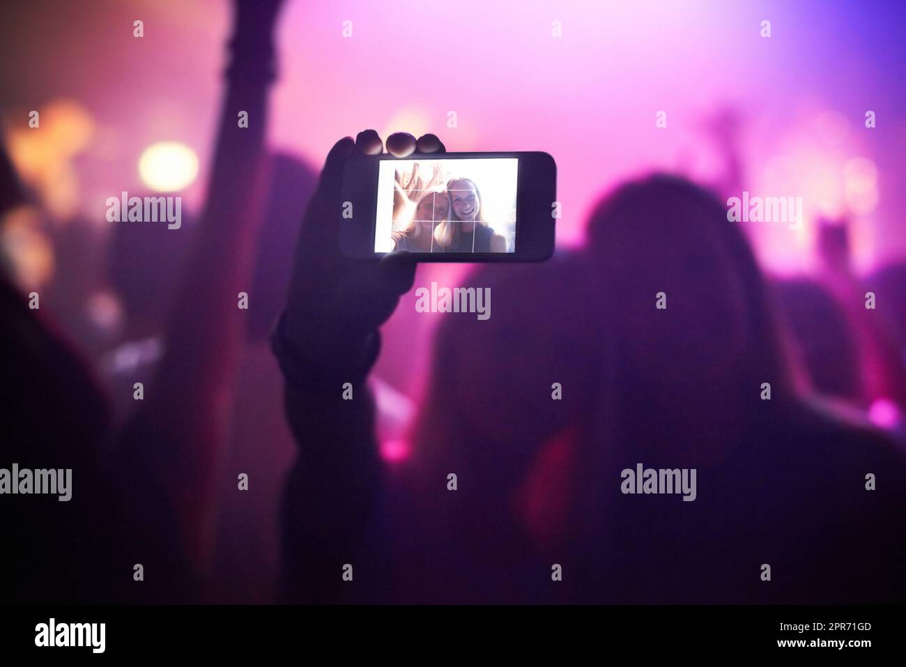 Shot of a fan filming a concert on their camera. This concert was created for the sole purpose of this photo shoot, featuring 300 models and 3 live bands. All people in this shoot are model released. Stock Photo
