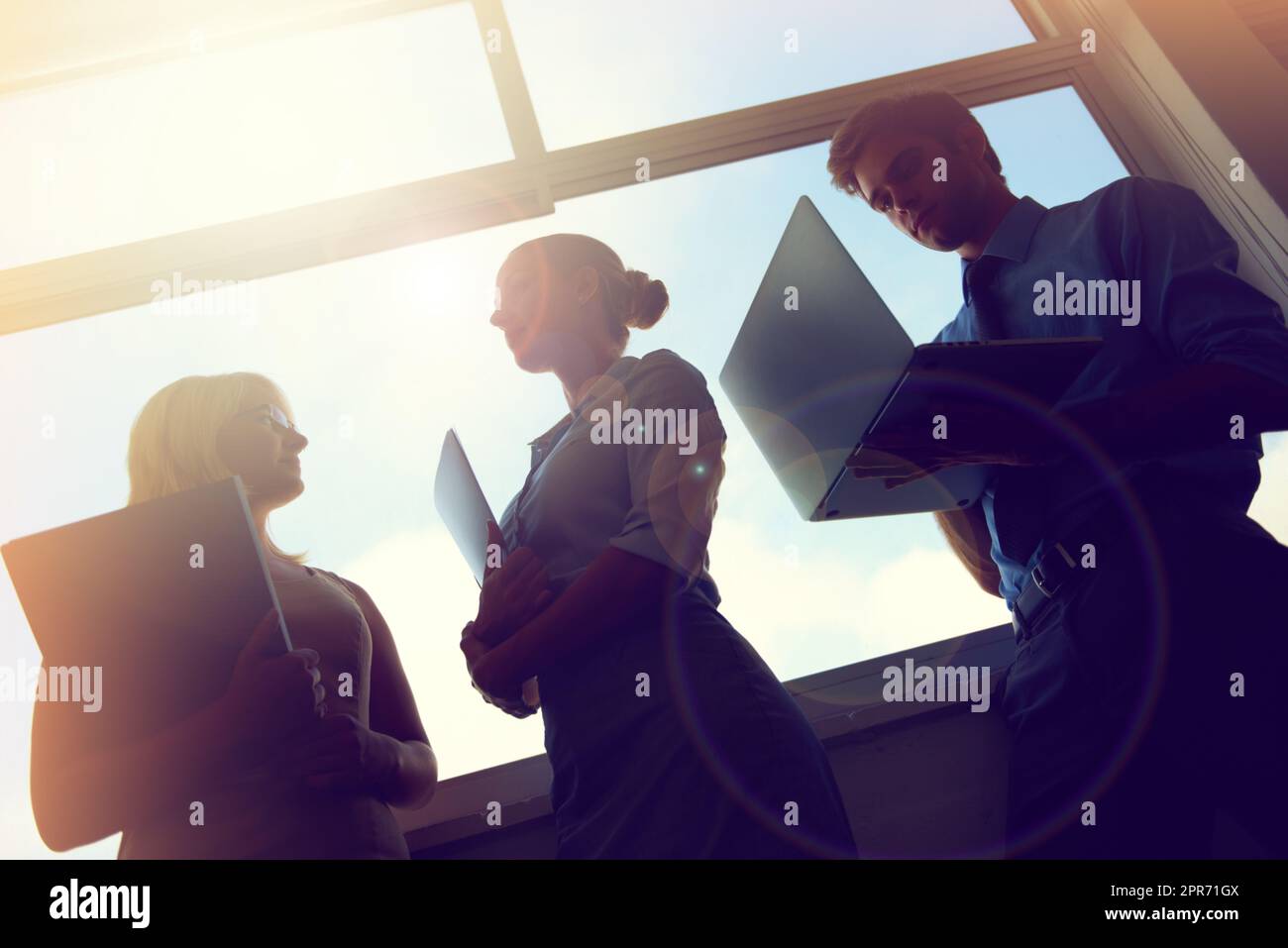 On their way to the top. Silhouette of three young businesspeople standing in front of a window. Stock Photo