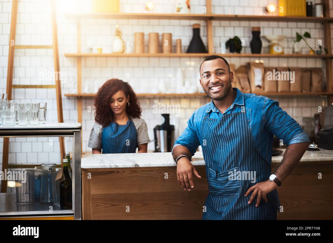 Our teamwork made our dream work. Cropped portrait of a handsome young man standing with his hand on his hip in his coffee shop. Stock Photo