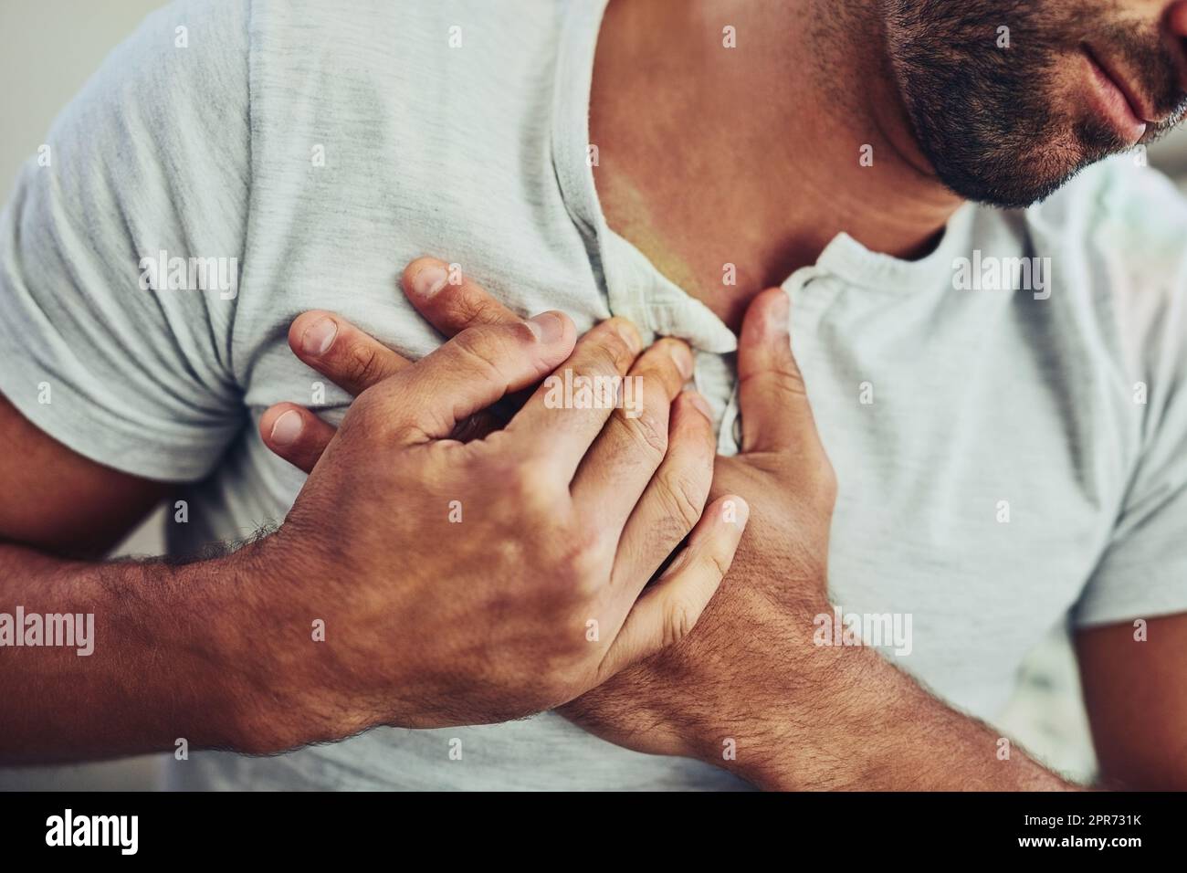Chest pain is the worst. Shot of a unrecognisable young man holding his chest in discomfort with his hands due to pain in that area. Stock Photo