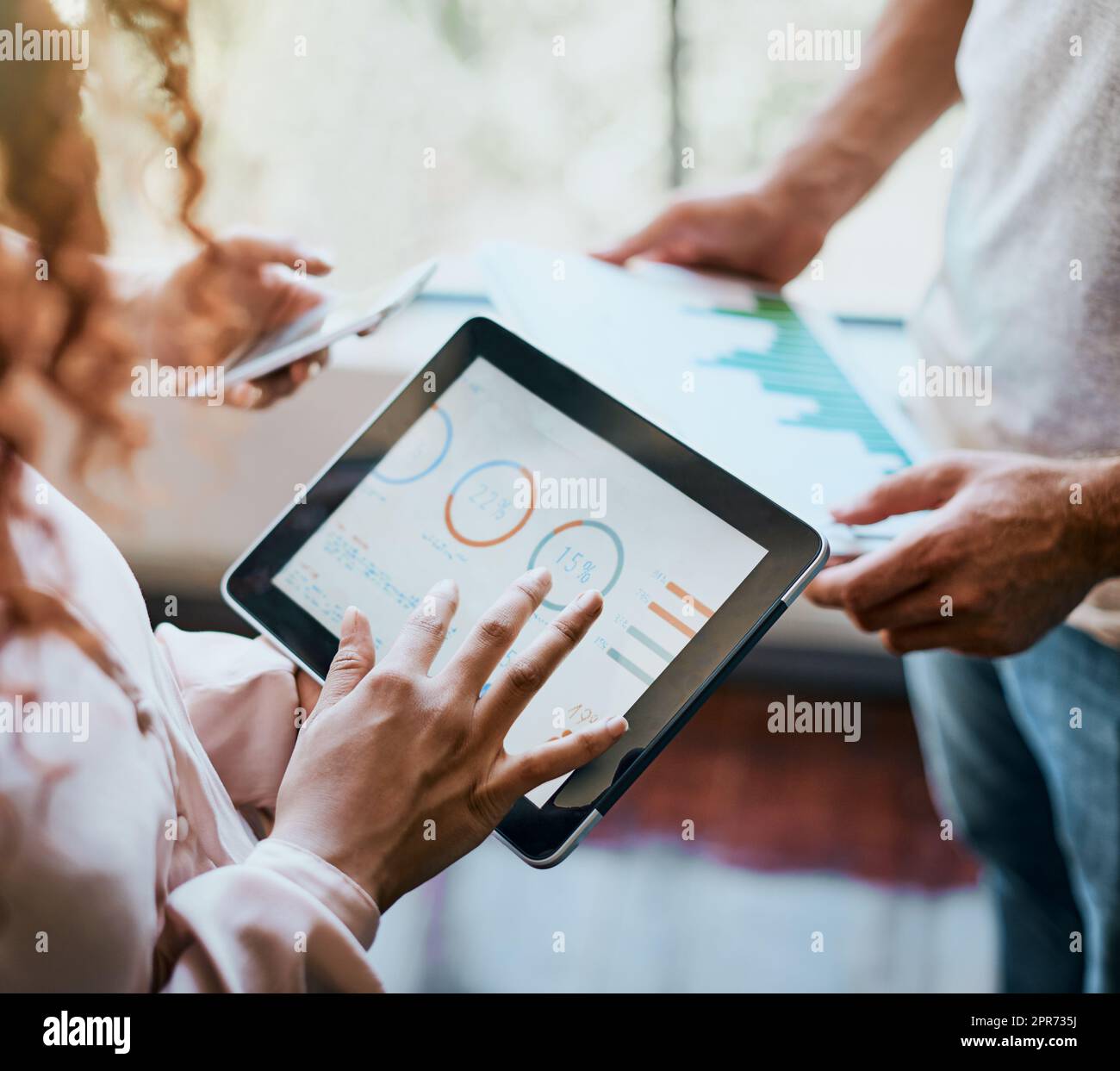 The calculations have been made. Shot of two unrecognizable peoples hands working on a tablet and looking at the businesss charts in the office. Stock Photo