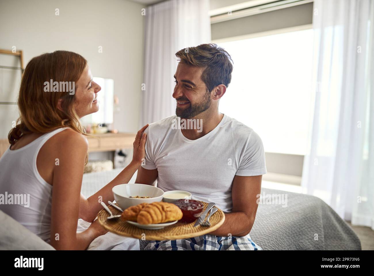 Romance is, breakfast in bed. Shot of a happy young couple enjoying breakfast in bed together at home. Stock Photo
