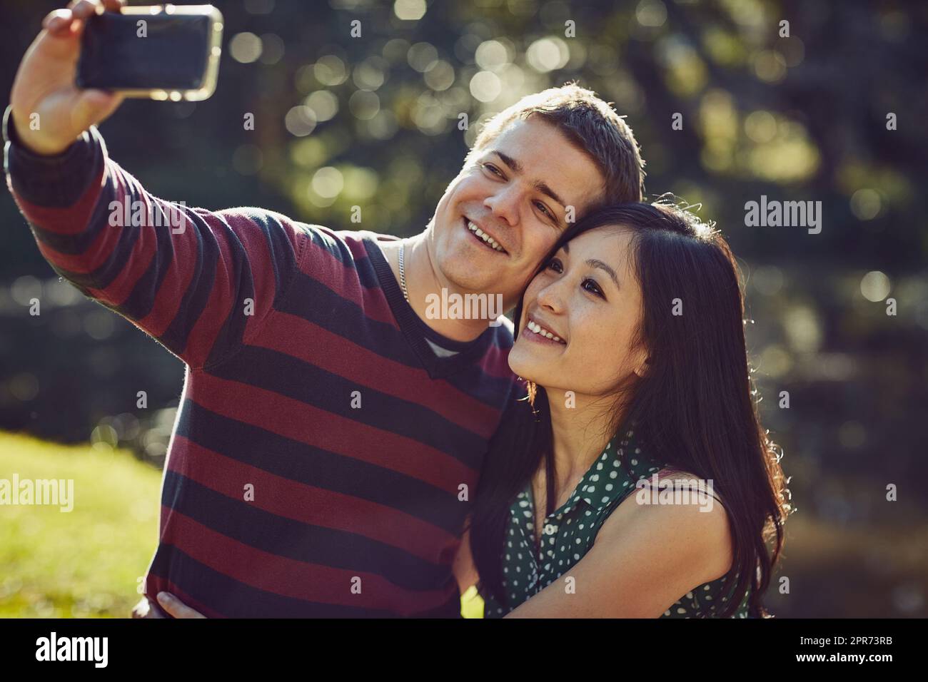 Where theres romance, theres a selfie. Shot of a happy young couple taking a selfie together in the park. Stock Photo