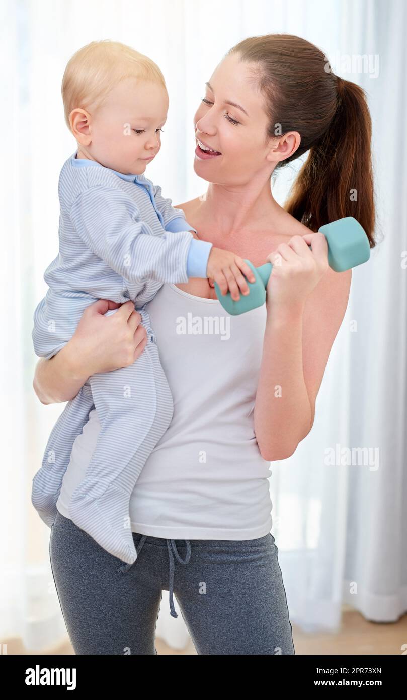 Youre going to be a strong young man. Shot of a young woman working out while spending time with her baby boy. Stock Photo