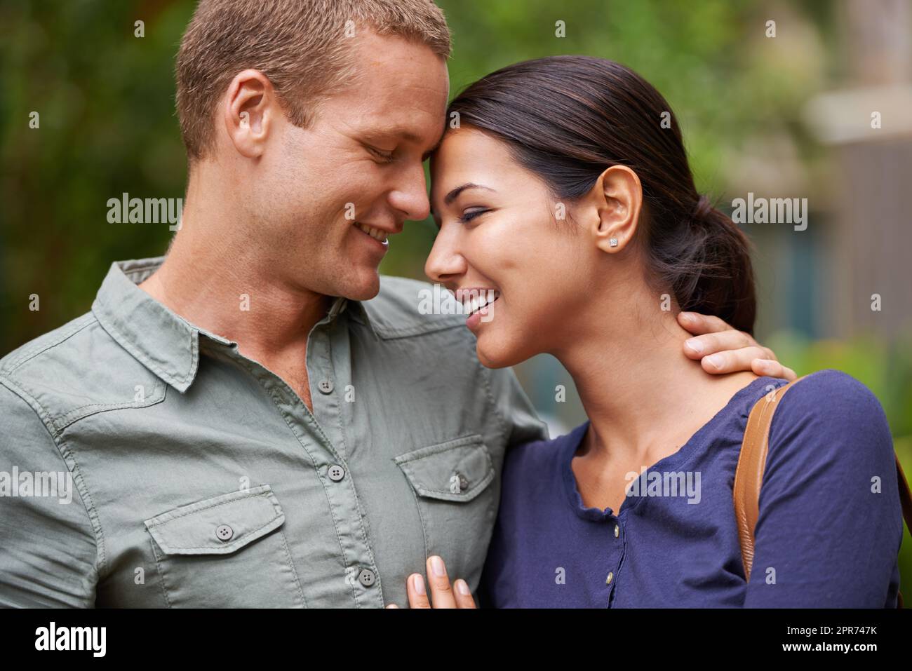 Lost in the haze of springtime romance. Cropped view of a happy young couple standing together out in the park. Stock Photo