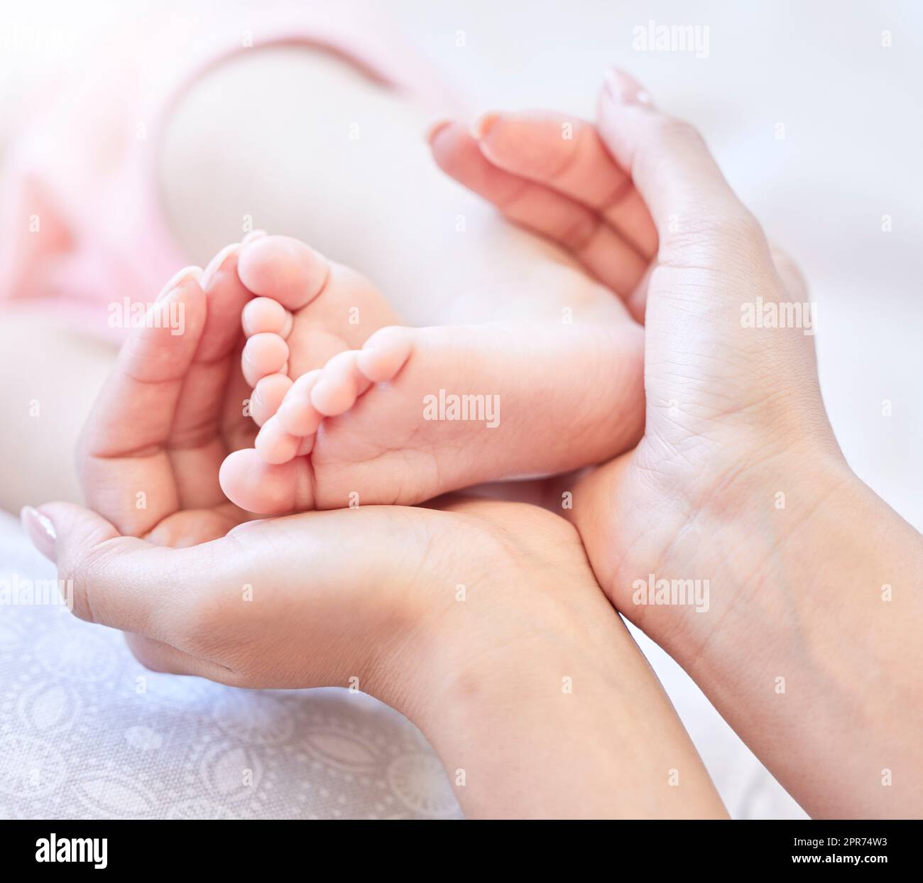 Mother holding baby feet. Closeup of tiny newborn baby feet held by a