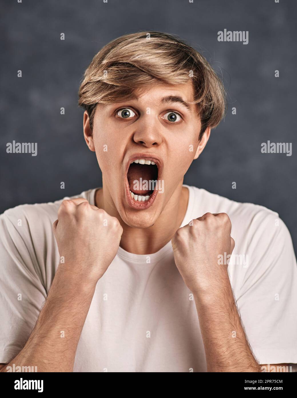 Crying emotional angry young man screams on gray background. Stock Photo