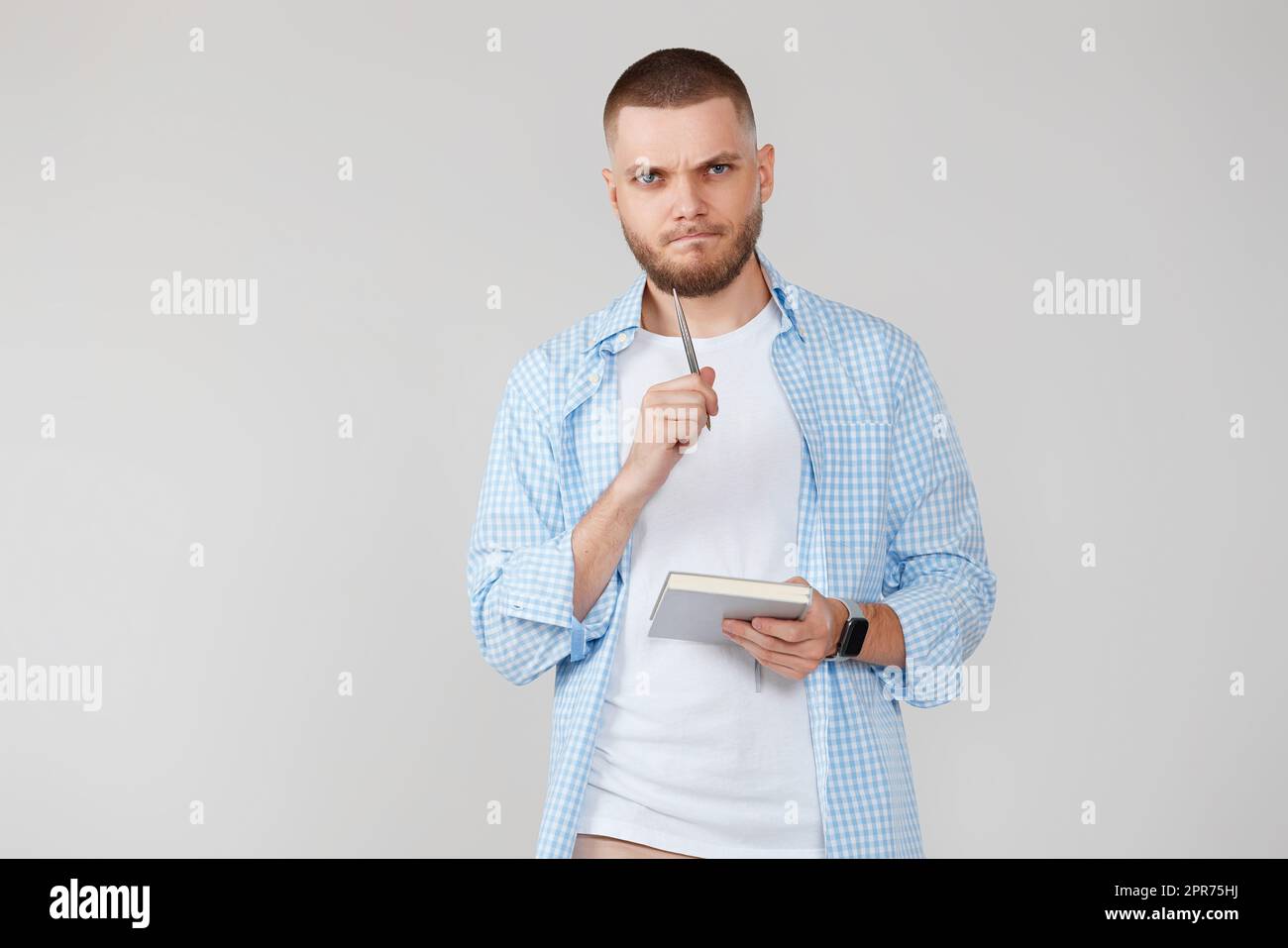handsome man in blue shirt writing note in notebook Stock Photo