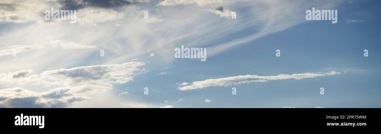 Light clouds in a calm blue sky with copy space background. A beautiful clear summer sky with sunshine and a white soft textured cloudscape in nature. relaxing skies clearing up on a sunny day Stock Photo
