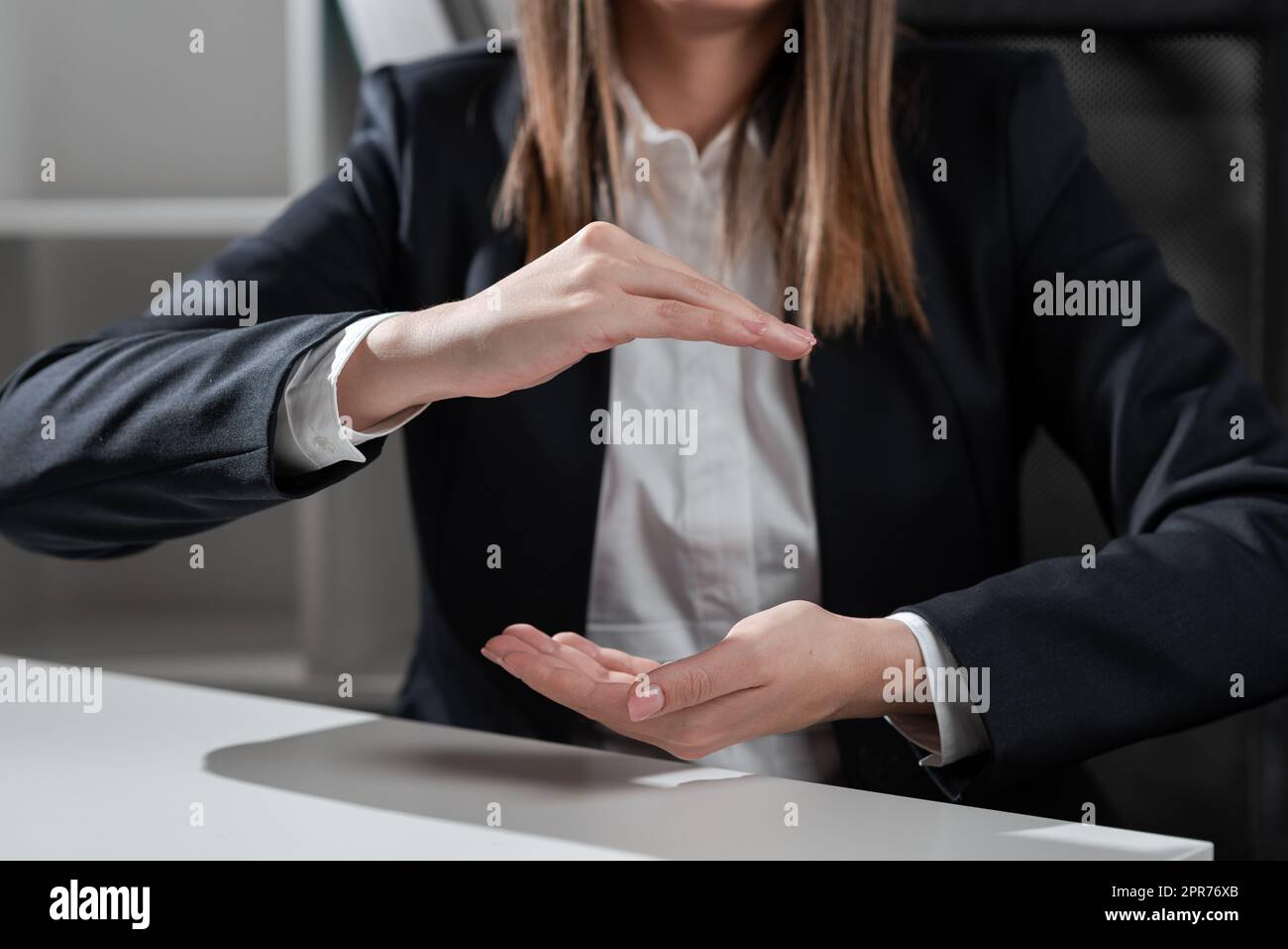 Businesswoman Holding Important Message Between Hands. Woman In Suit Showing New Crutial Idea Among Palms. Executive Presenting Updated Critical Information. Stock Photo