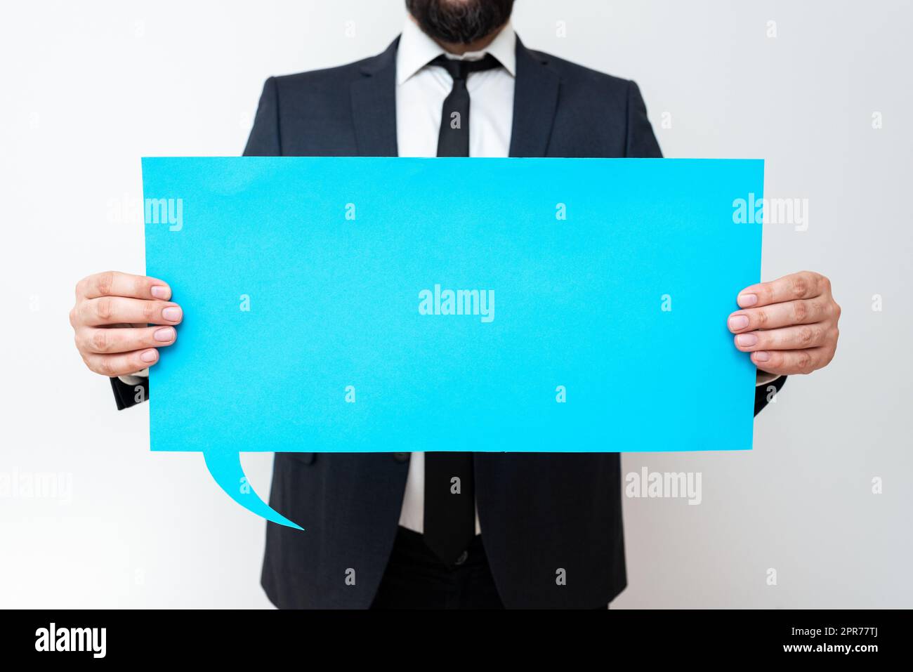 Businessman Holding Speech Bubble With Important Messages. Man In Suit Presenting Crutial Informations On Dialogue Balloon. Gentleman Showing Recent Updates On Paper. Stock Photo