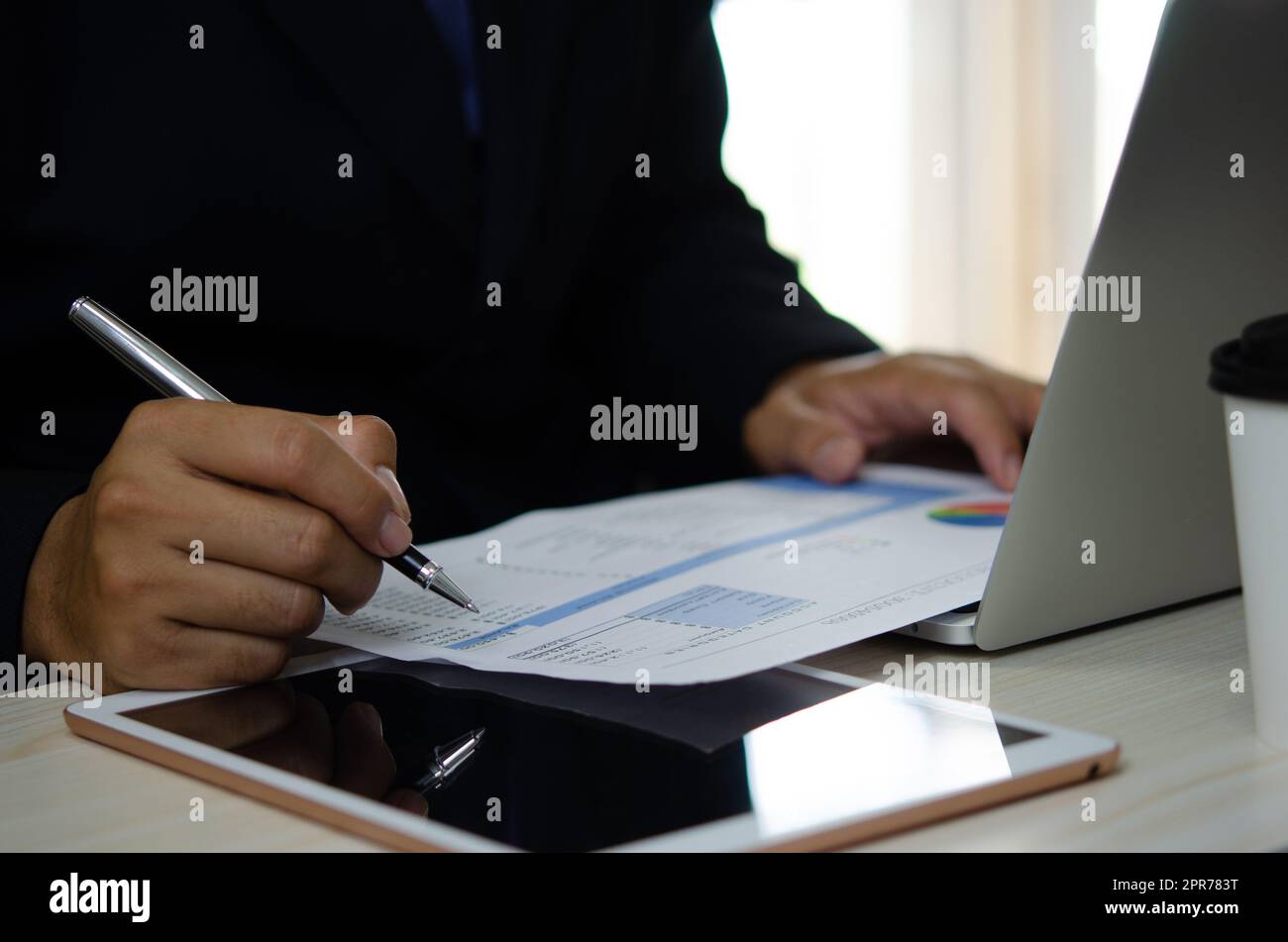 businessman holding pen to work computer graphs and charts data statistical data financial analysis documents. Stock Photo