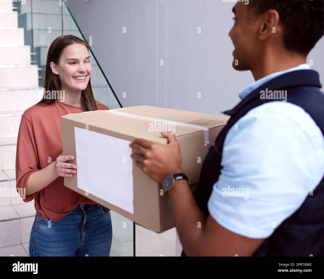 Im glad that I caught you. Shot of a woman accepting her delivery from the delivery man. Stock Photo