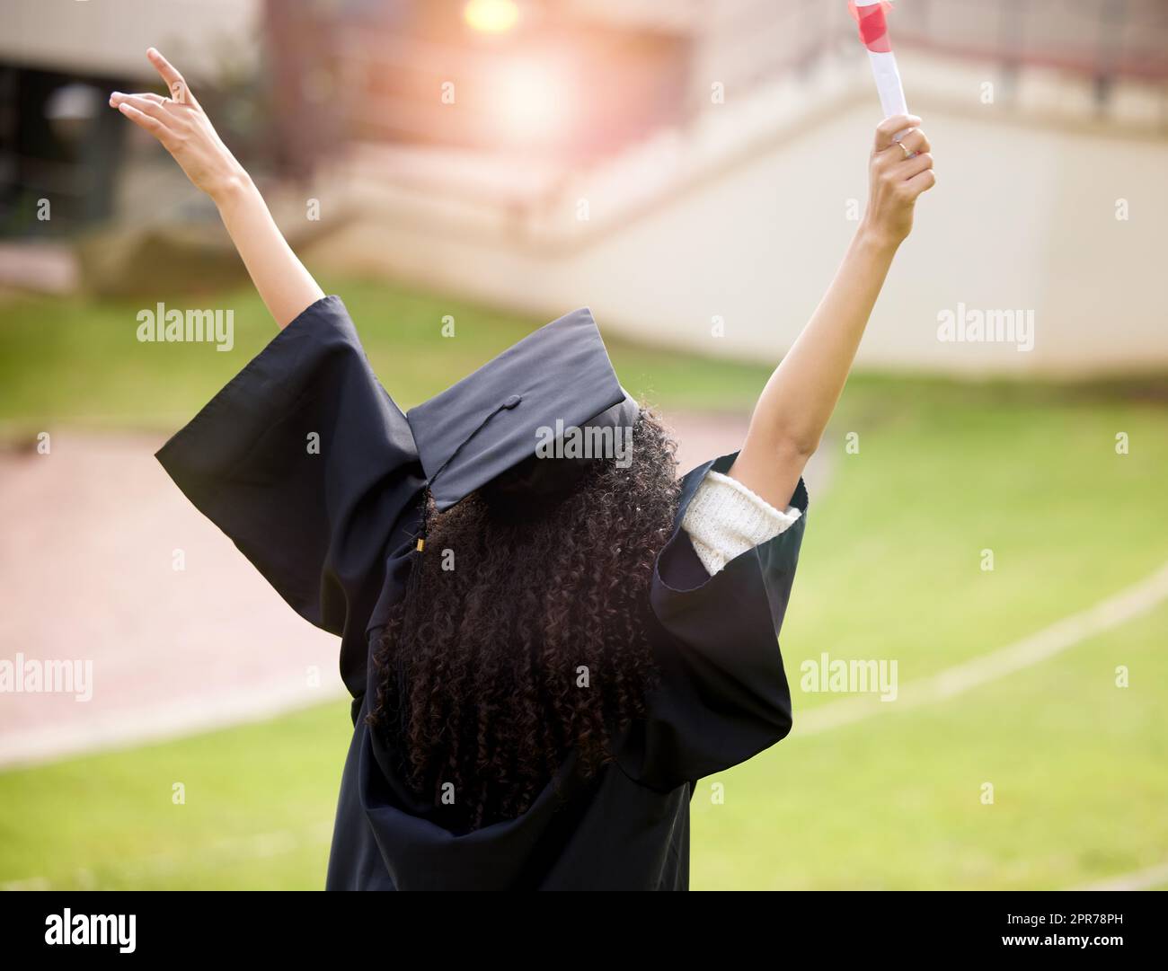 I have even further to soar. Rearview shot of a young woman cheering on graduation day. Stock Photo