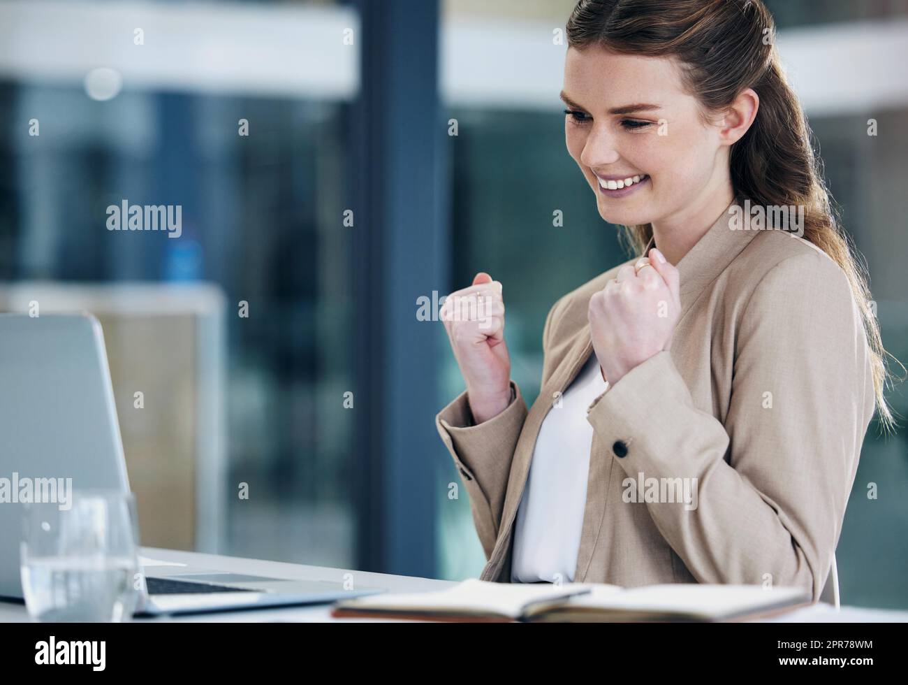 The offer Ive been wanting just came through. Shot of a young businesswoman cheering while working on a laptop in an office. Stock Photo