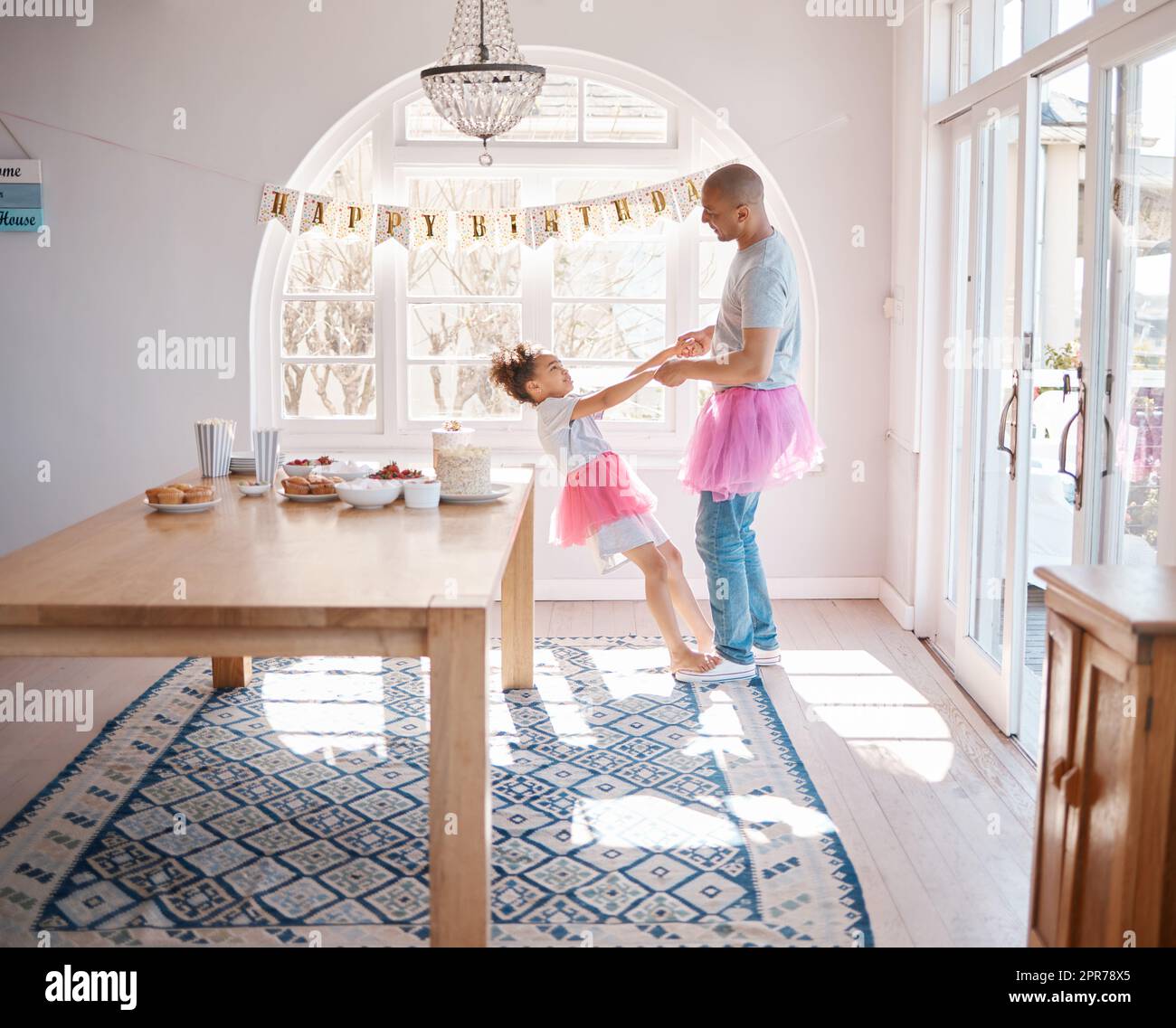 Celebrate and be your very happiest. Shot of an adorable little girl wearing a tutu and dancing with her father in the living room. Stock Photo