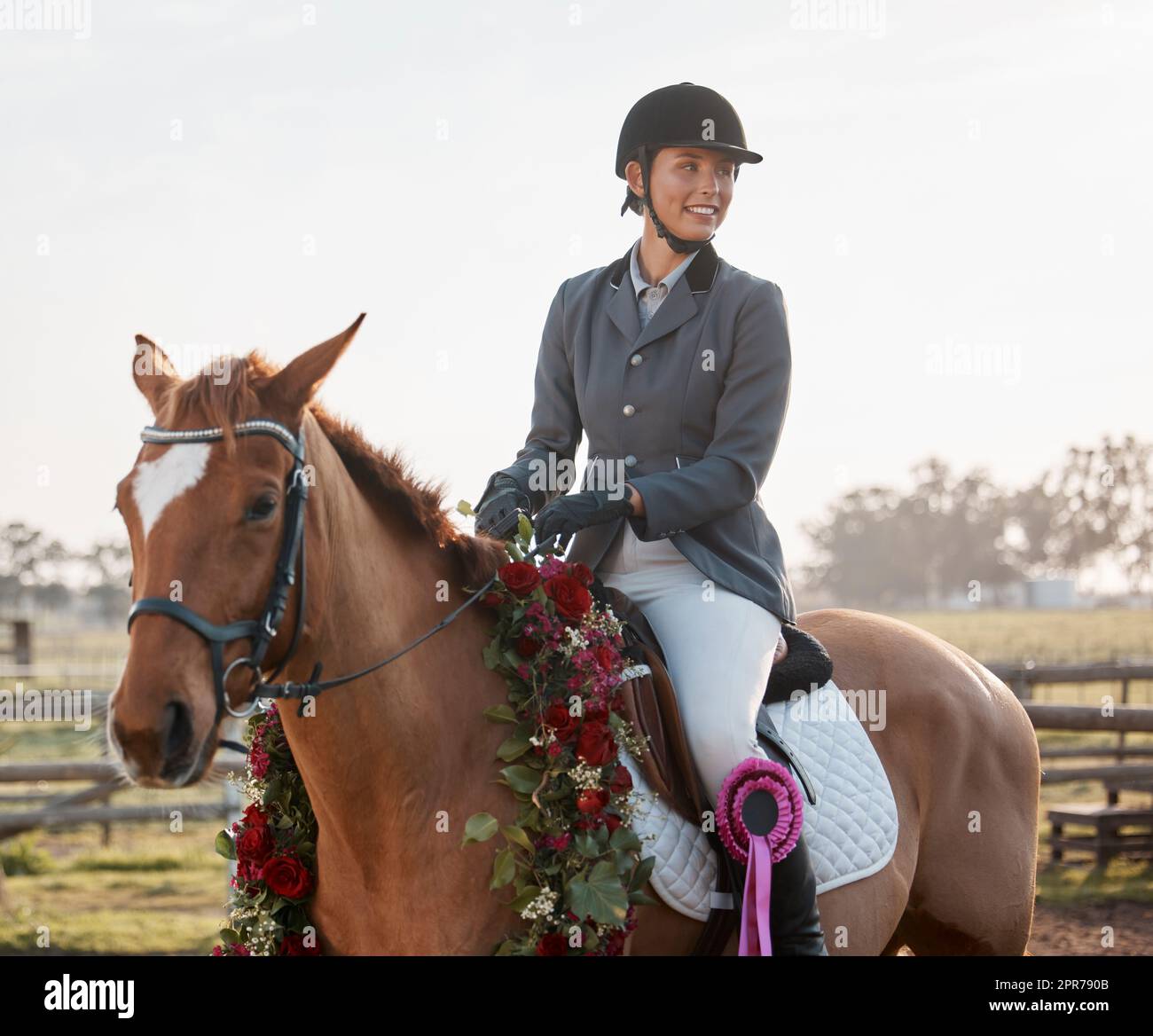 The winning team. Cropped shot of a young female jockey sitting on her wreathwearing horse