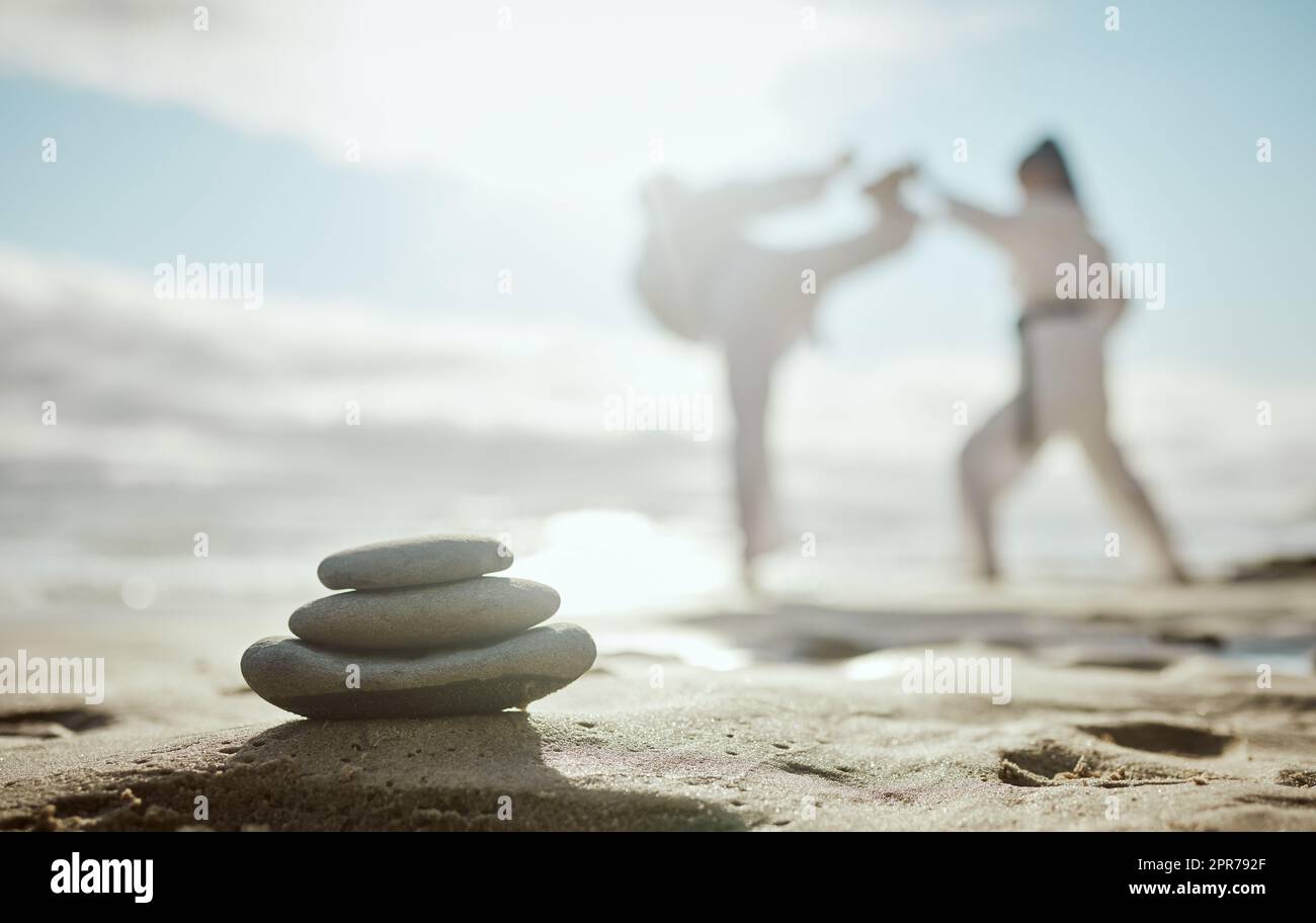 The mind of a fighter should always be calm and calculated. Full length shot of two unrecognizable martial artists practicing karate on the beach. Stock Photo