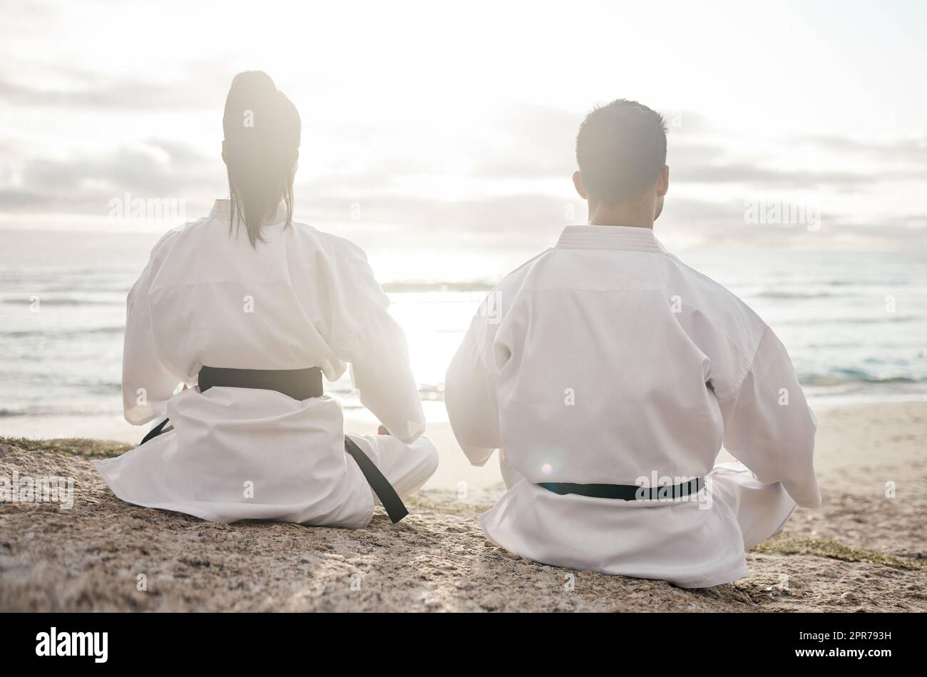 A fighters state of mind. Rearview shot of two unrecognizable martial artists meditating while practicing karate on the beach. Stock Photo