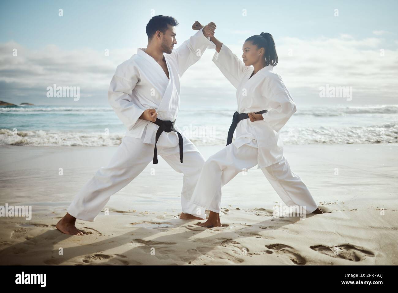 Its important to know self defense. Full length shot of two young martial artists practicing karate on the beach. Stock Photo