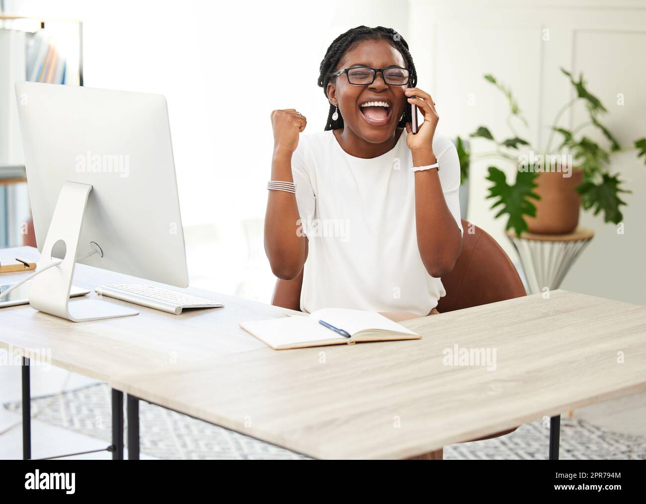I cant believe I did it. Shot of a young businesswoman cheering while on a call at work. Stock Photo