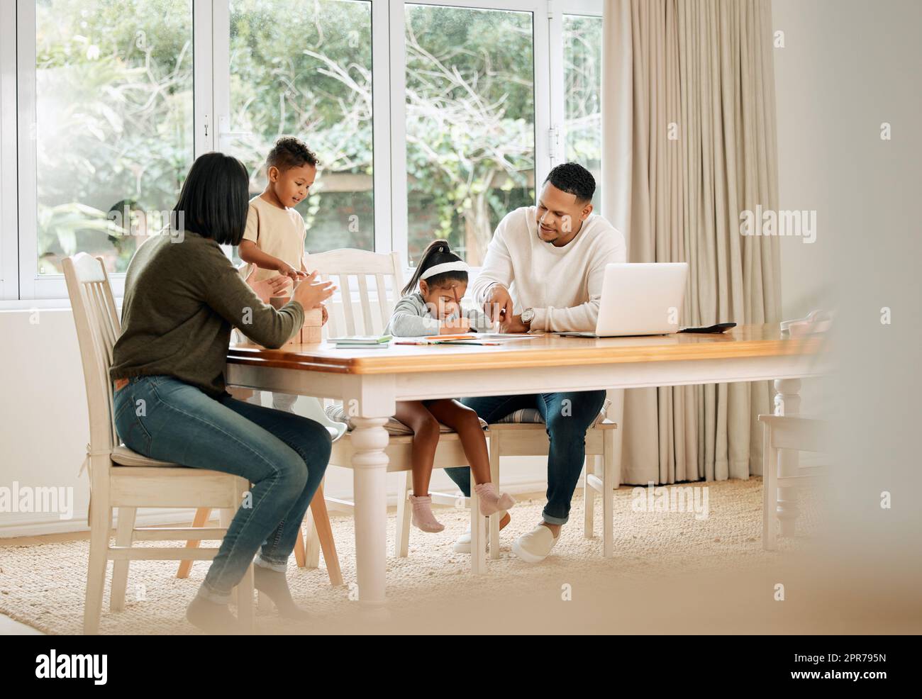 These are the times. Shot of a young family doing homework together at home. Stock Photo