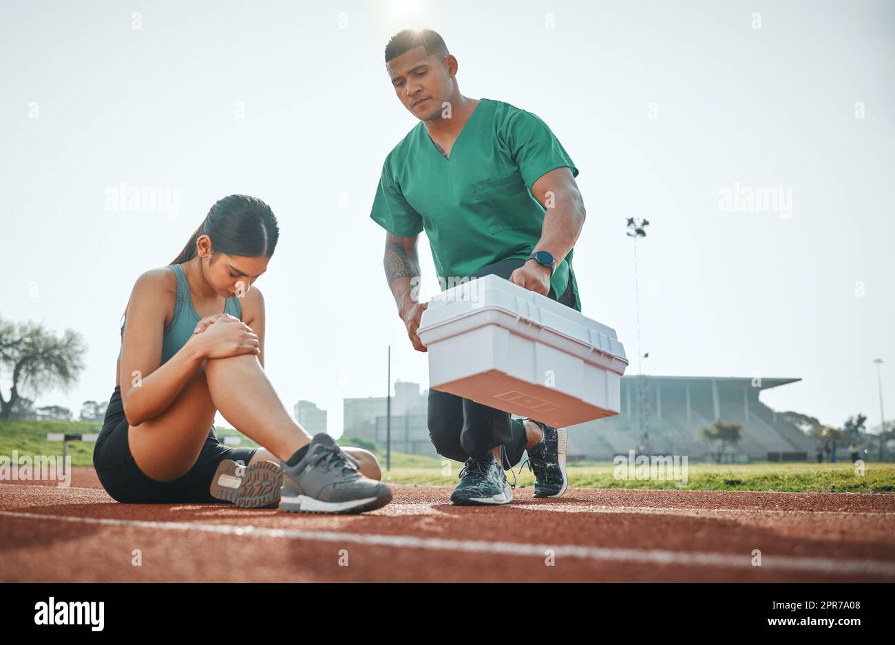 Rushing to the scene for medical attention. a sports paramedic providing first aid to an athlete on a running track. Stock Photo