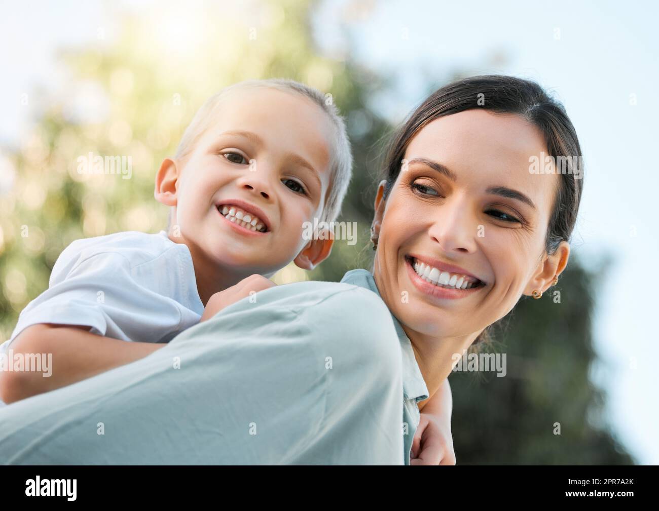Are you ready for the ride. a beautiful woman piggybacking her son at the park. Stock Photo