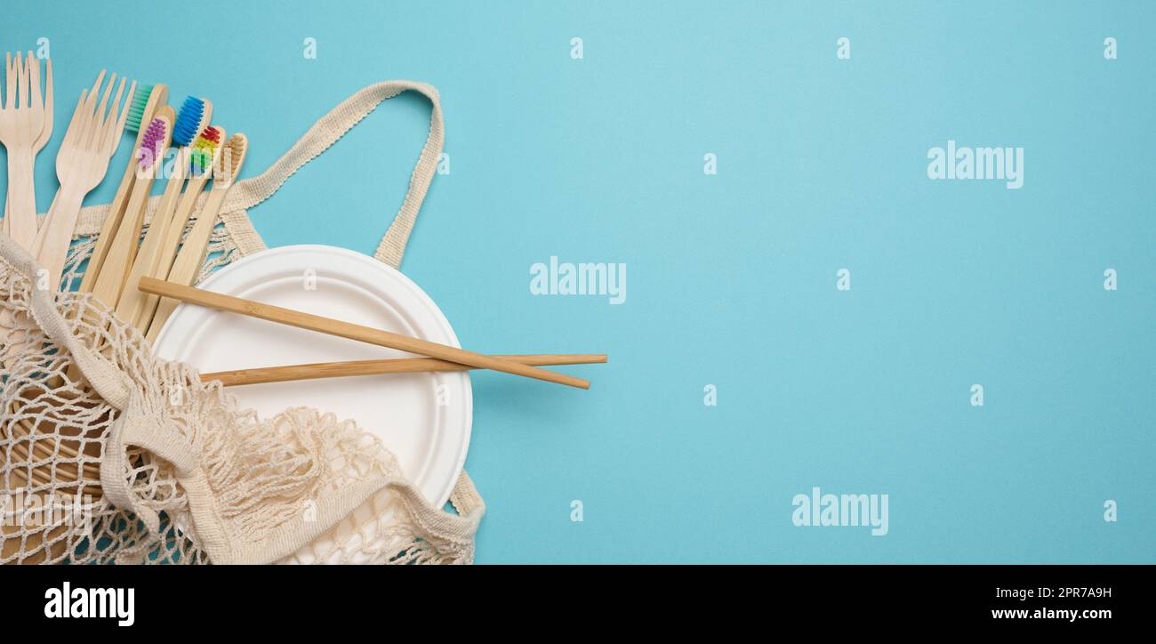 White textile bag and disposable tableware on a blue background. Stock Photo
